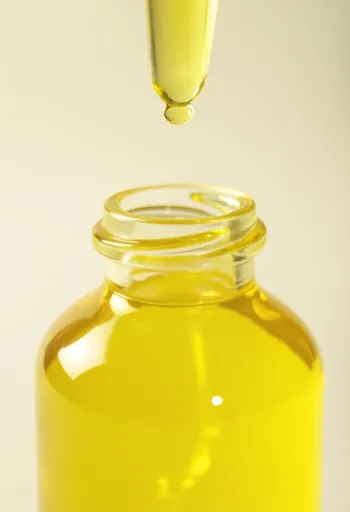 בקבוקון שמן לימון לצד פלחי לימון טריים וסלילי קליפה